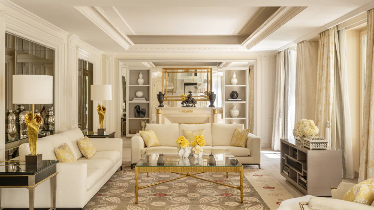 Elegant luxury hotel suite with two off-white sofas, crown molding and built-in shelves