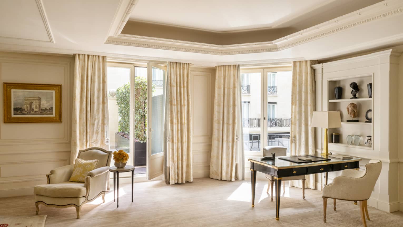 Light-filled elegant hotel room with a writing desk and chaise
