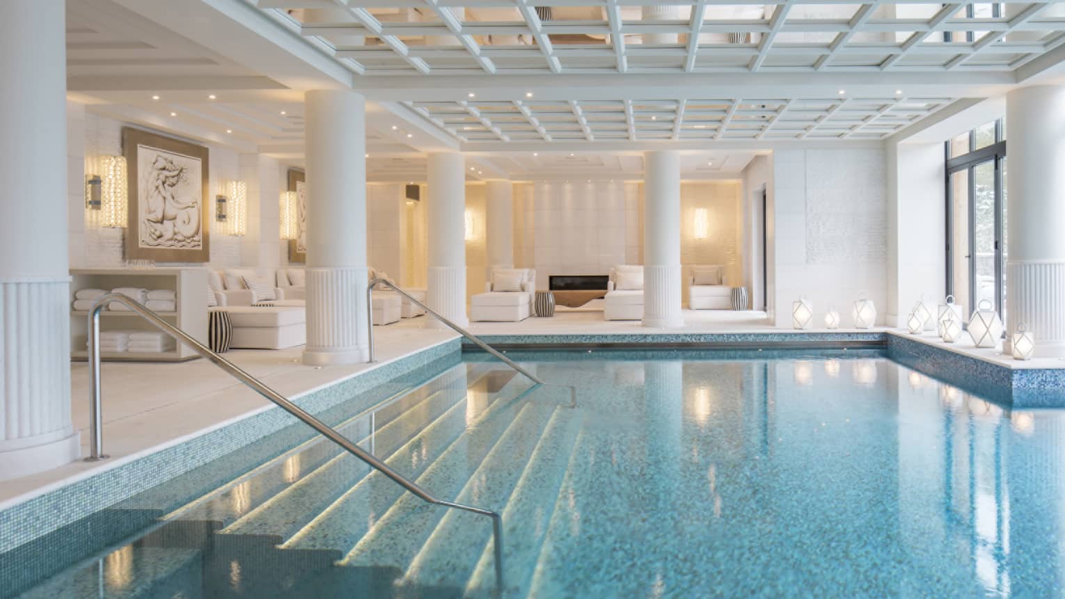 An indoor pool with a glass ceiling above it in a well lit room.