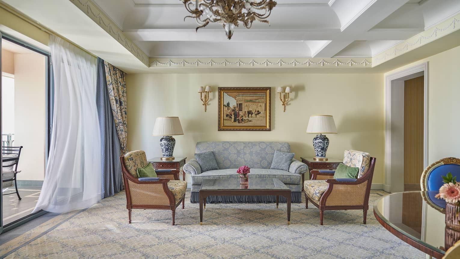 Deluxe Two Bedroom Suite living area with couch, twin armchairs and coffee table, sliding glass door to veranda