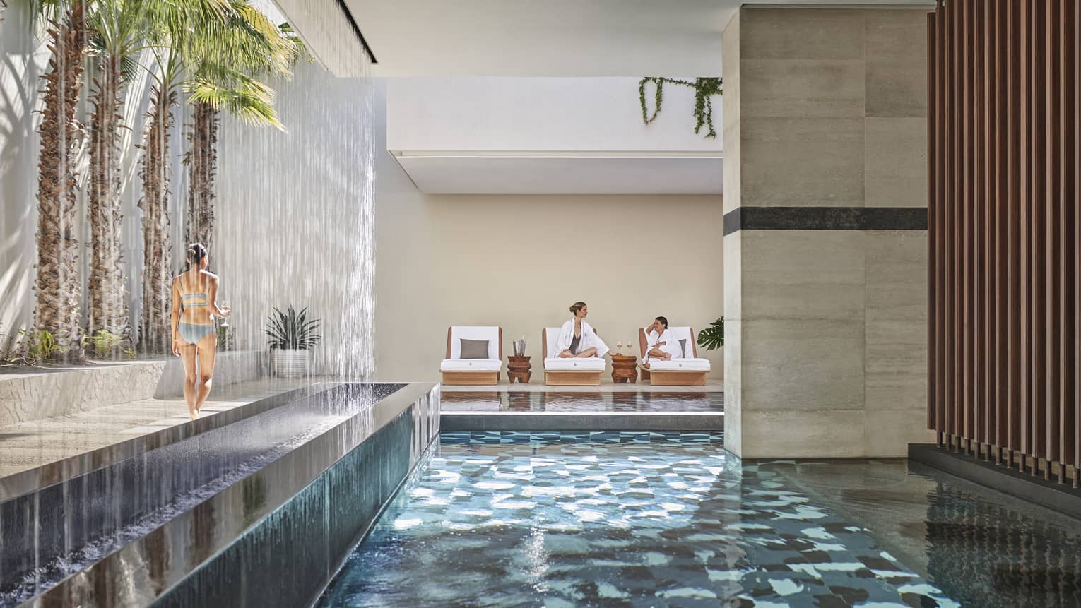 An indoor/outdoor spa area with a pool, palm trees, and lounge chairs.