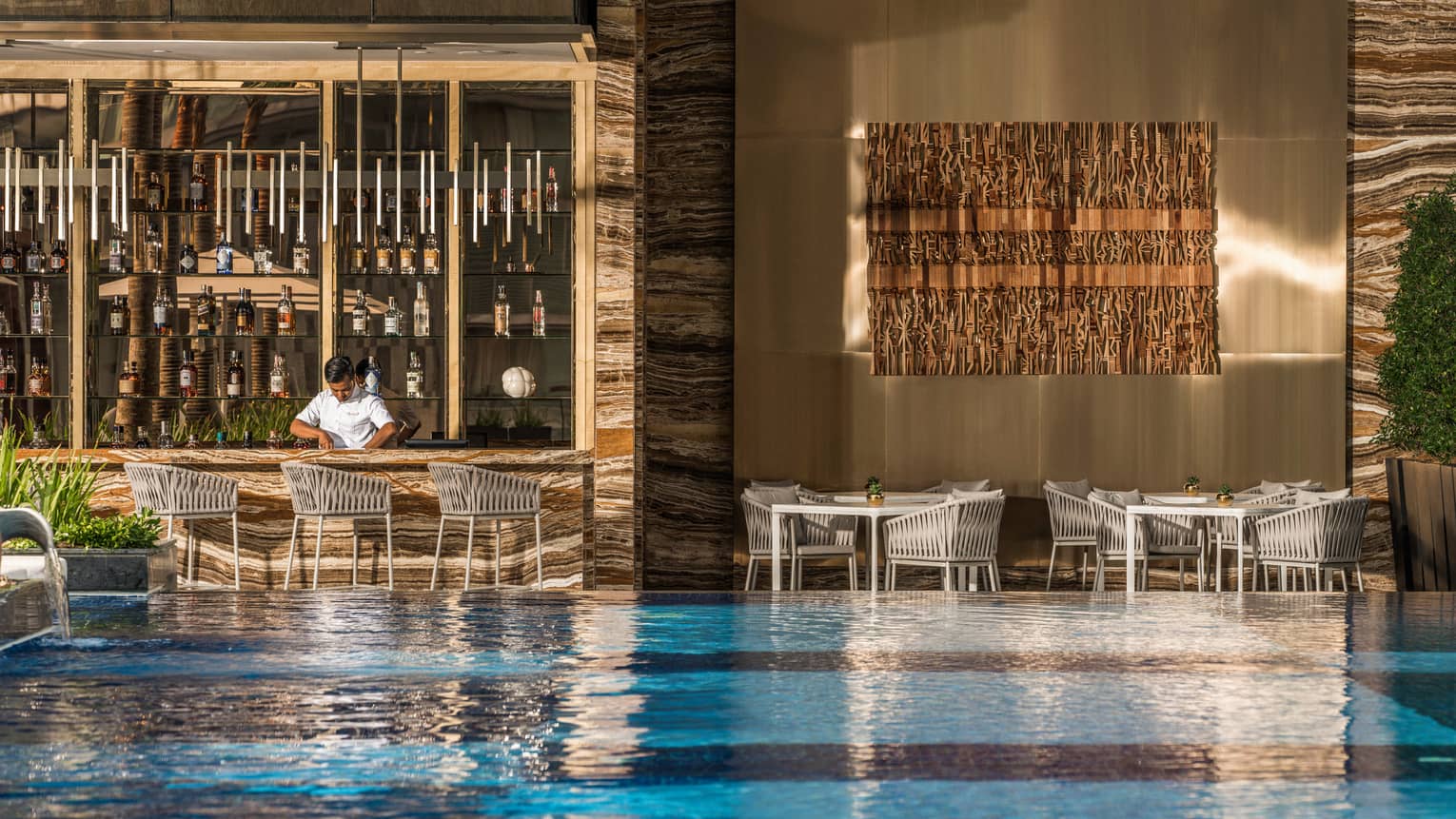 Pool bar and grill with view of pool and bartender