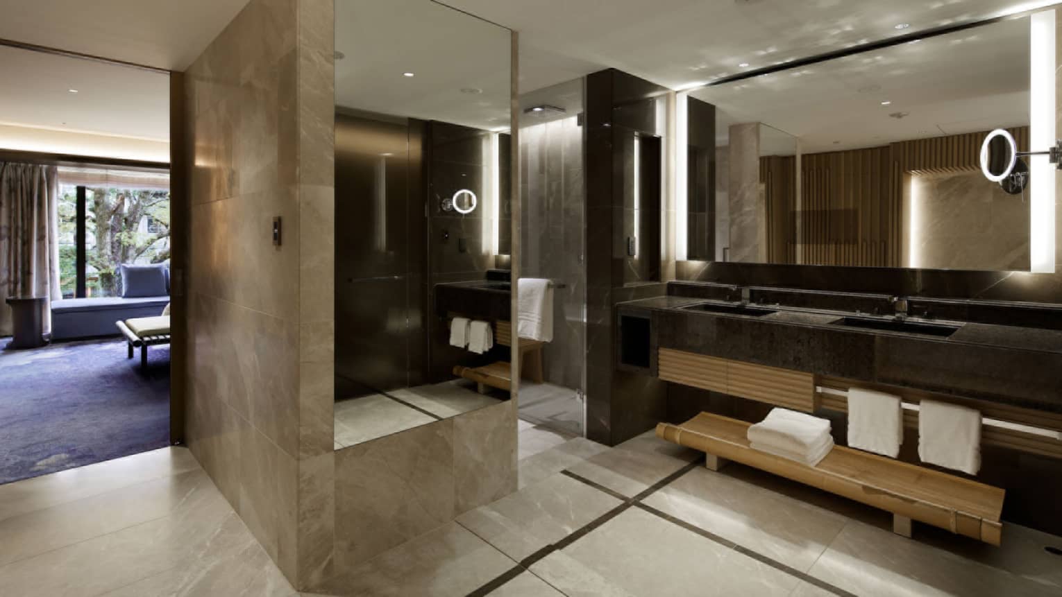 Spacious bathroom with a double-sink vanity, large mirrors and marble wall accents, connecting to the bedroom
