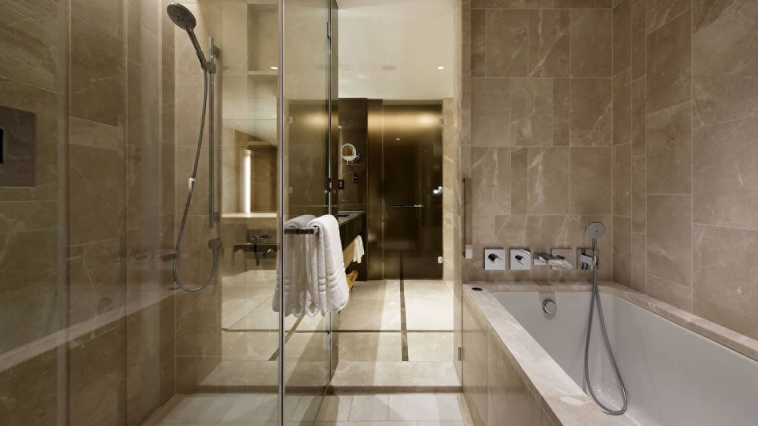 Modern hotel bathroom with a glass-enclosed shower, marble walls and a spacious bathtub at Four Seasons