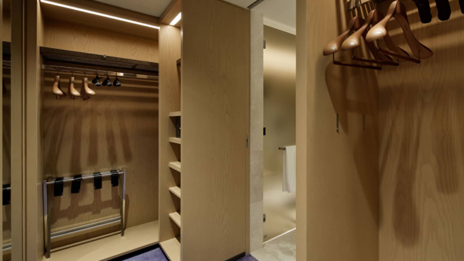Spacious walk-in wardrobe with wooden shelving, hangers and soft lighting