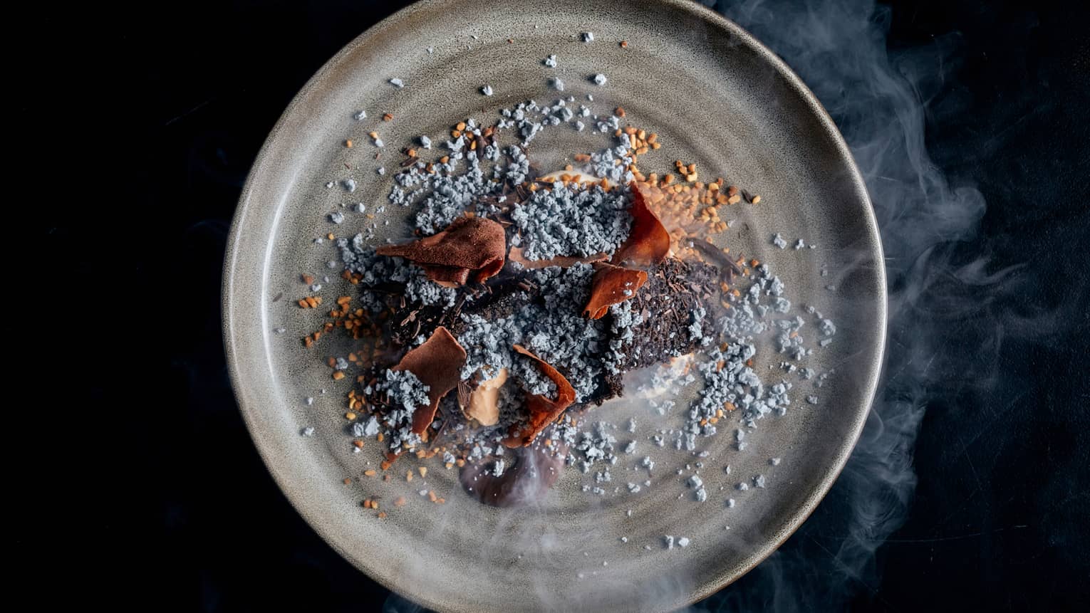 Hazelnut, chocolate and toasted rice on a grey plate.