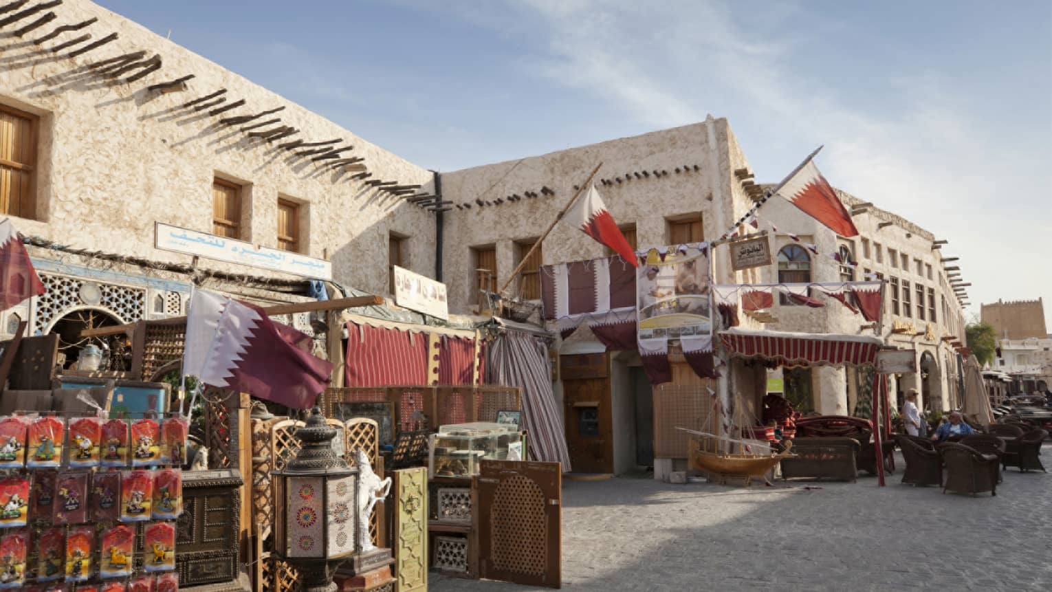 Souq Waqif outdoor market, stalls and goods along white stone buildings, road 