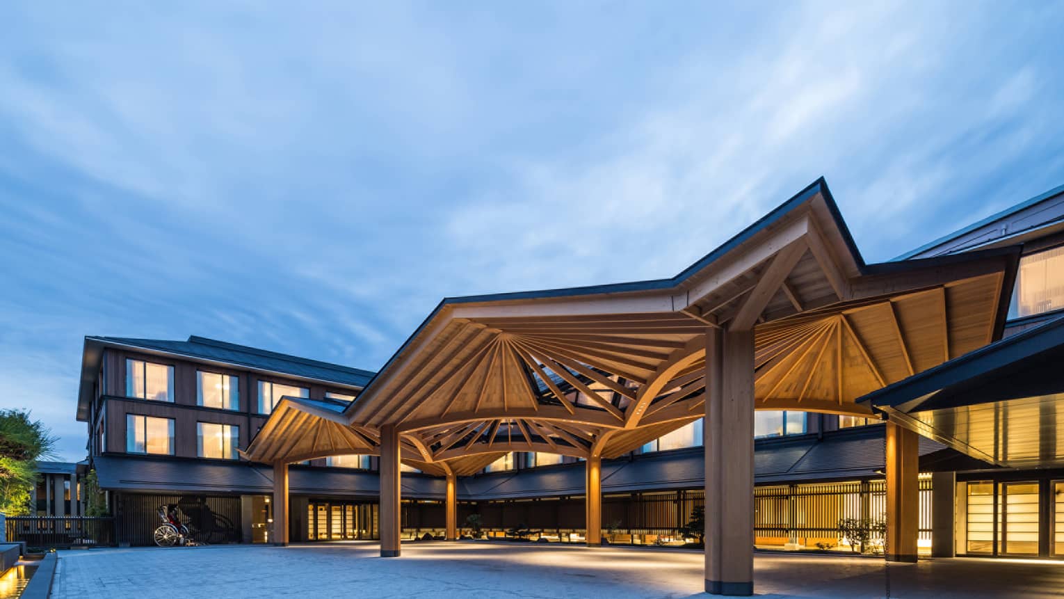 Entrance courtyard of Four Seasons with illuminated wooden pavilion structures in the evening