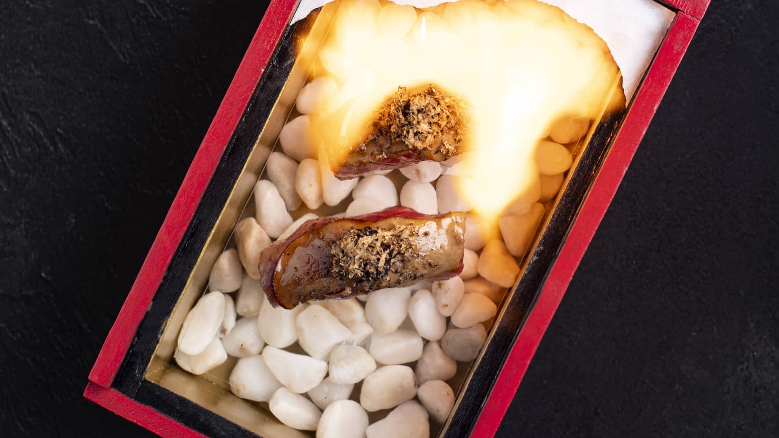 Overhead view of two slices of wagyu beef on a small stone-fire grill