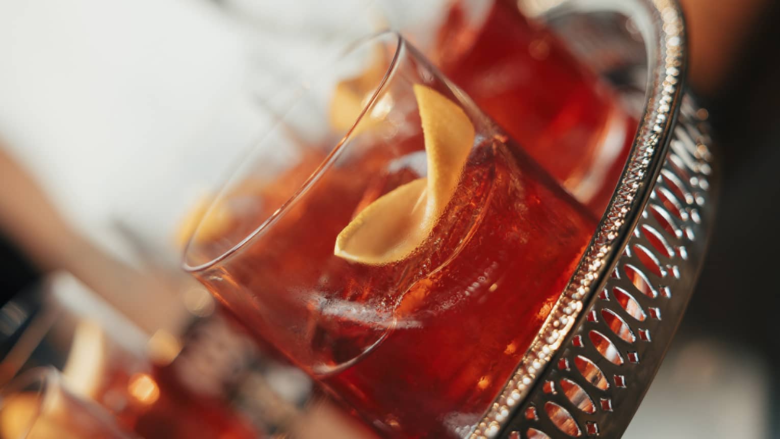 Four glasses of Old Fashioned cocktails on a silver tray