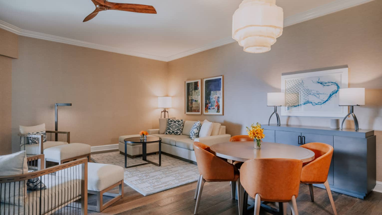Contemporary living and dining area with round table, orange chairs, beige sofa and modern artwork on neutral walls