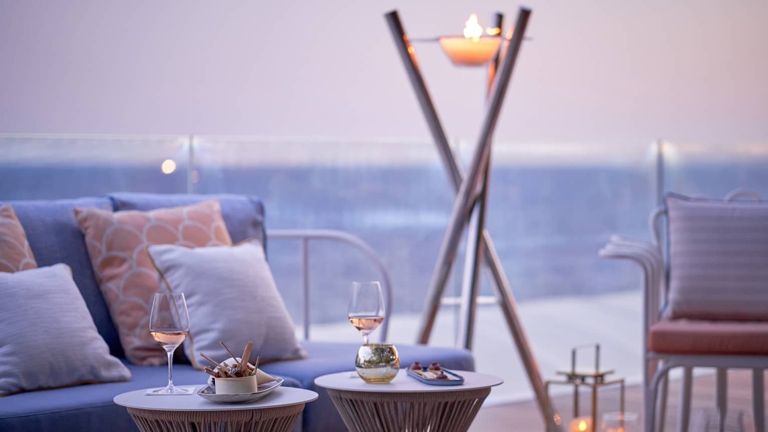 Club Dauphin terrace, blue love seats, orange pillows, candles, torch, sea view at sunset