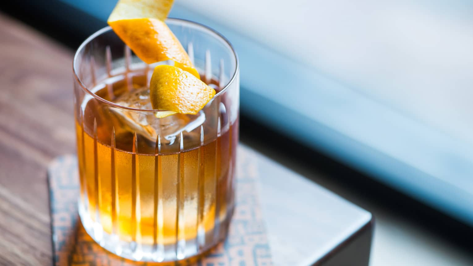 Rye whiskey cocktail in rock glass with ice cube, orange peel garnish