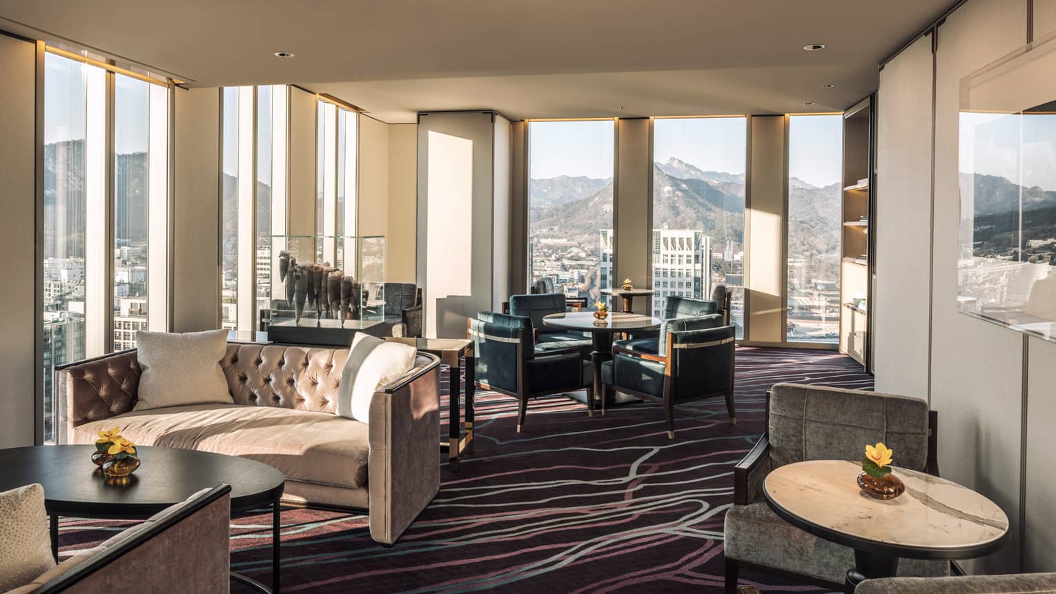 Lounge with tufted velvet sofas, cocktail tables and armchairs, floor-to-ceiling windows