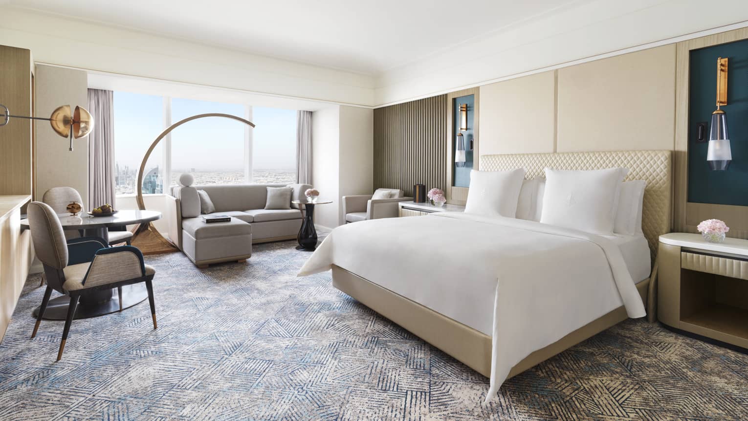 Hotel room with king bed, window-side sofa, and small table with two chairs