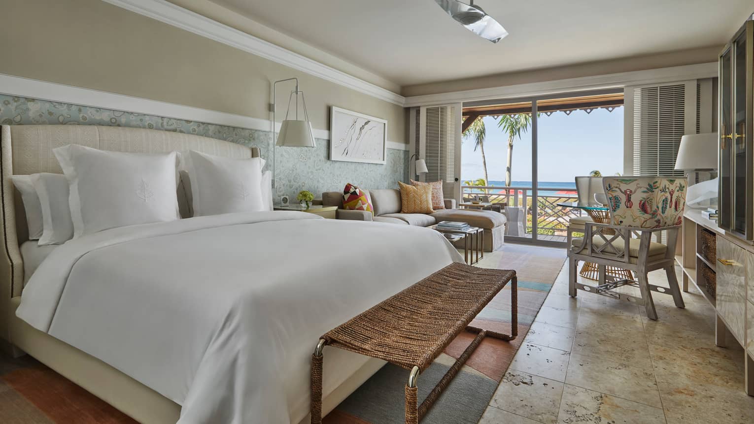 Ocean-View Room bed, wicker bench, chair, sofa by sunny balcony doors, shutters