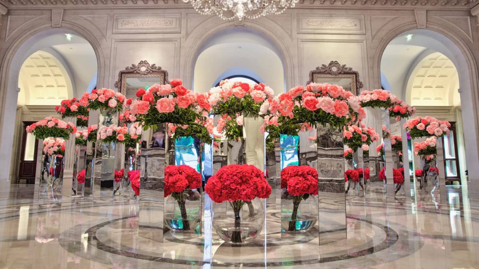 White marble lobby with multiple glass podiums with red and pink flower arrangements 