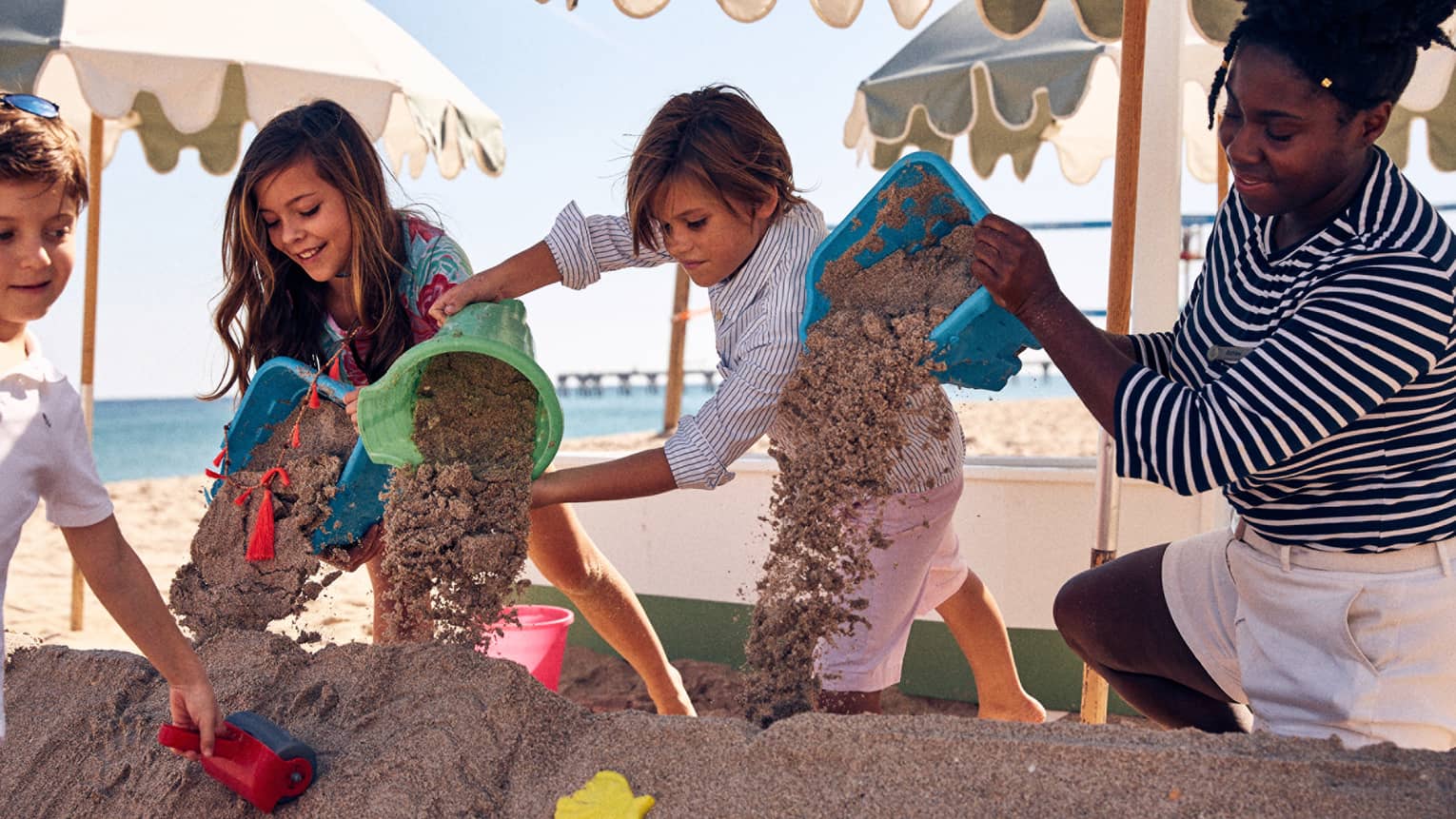 A group of kids playing with sand on a beach.