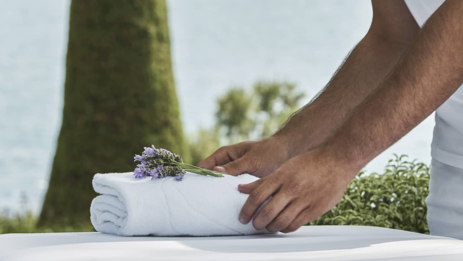Close-up of hands setting on folded white towel with lavender sprig