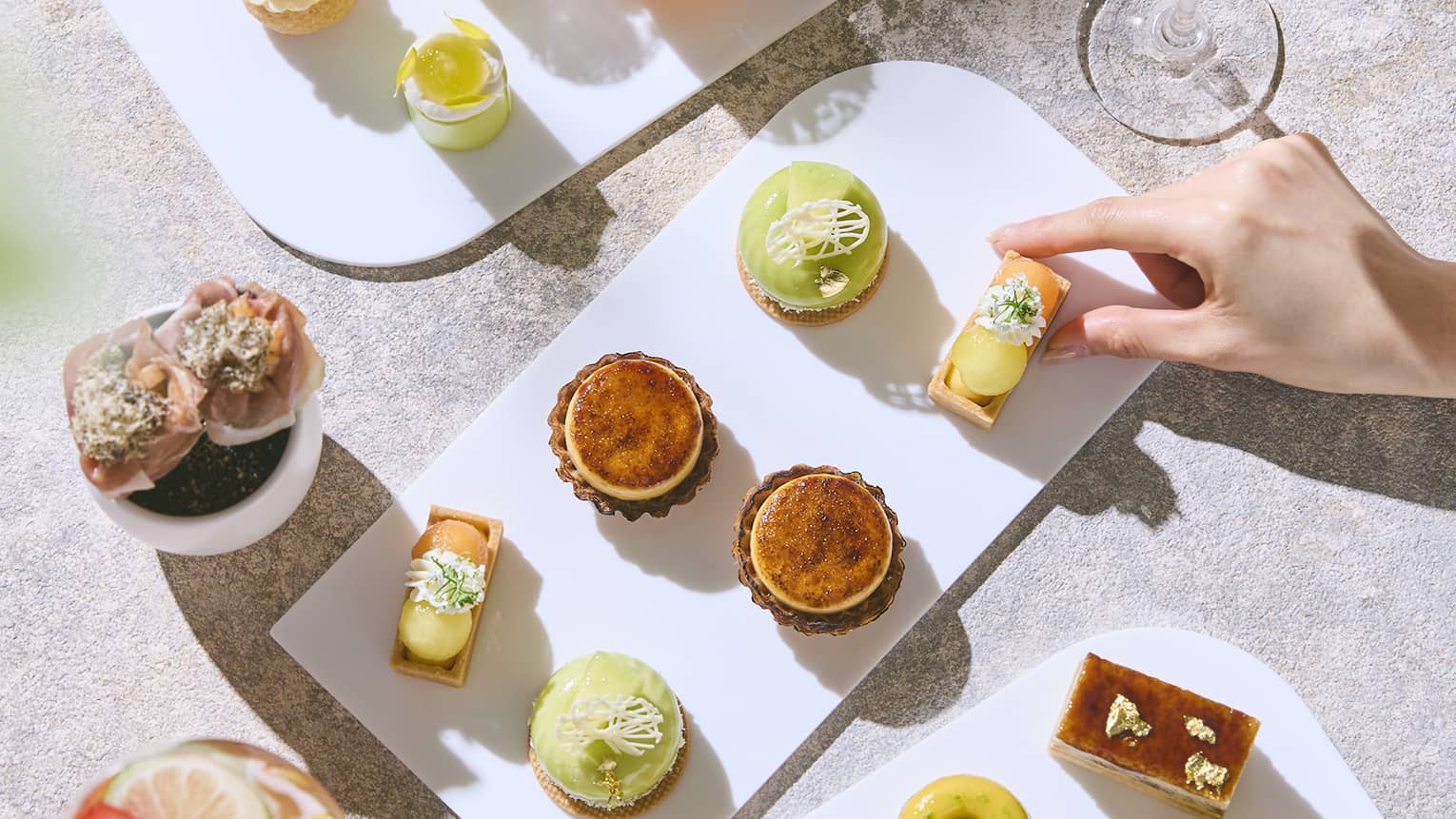 Platters of Afternoon Tea bites on a table, along with two drinks in stemmed glassware