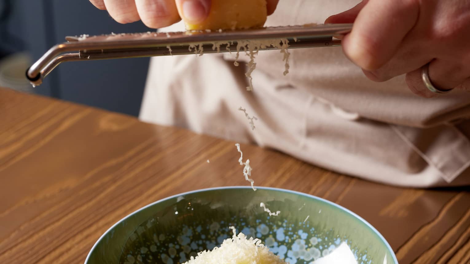 Chef grates Parmesan cheese over dish