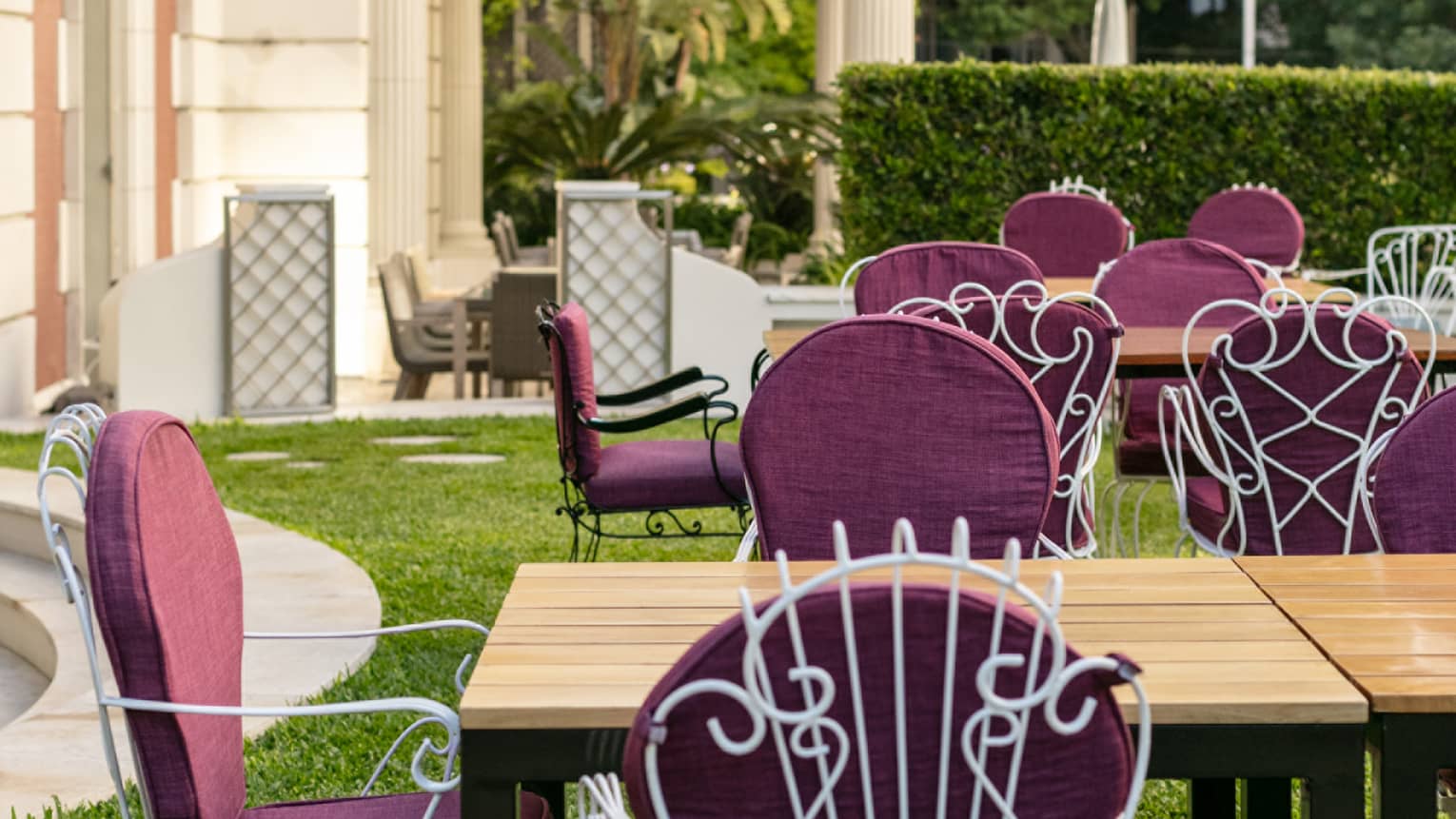 Several tables set up on a terrace with purple chairs. 