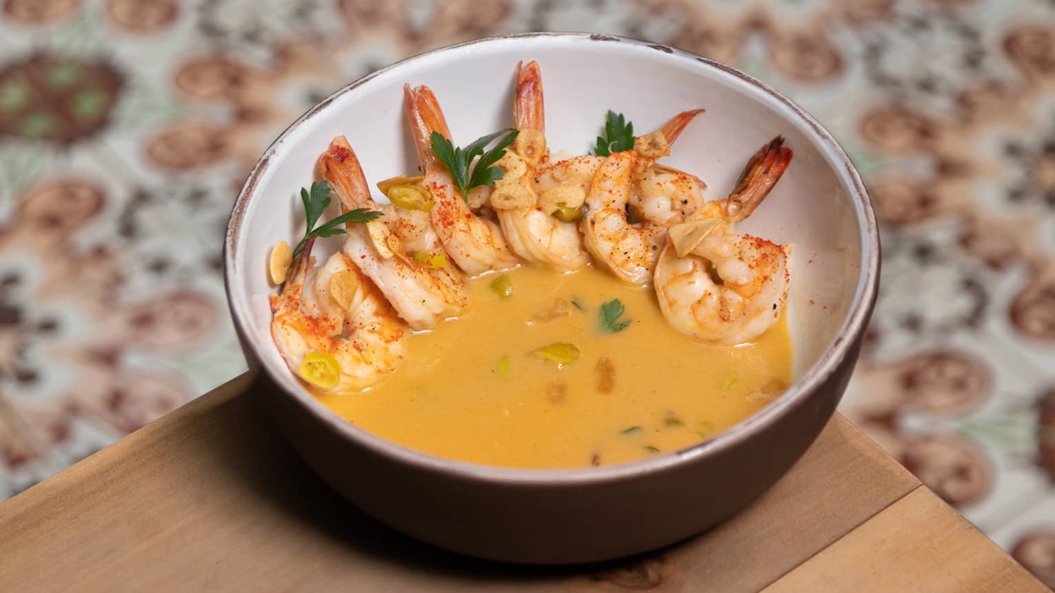 Shrimp in a yellow sauce served in a ceramic bowl.