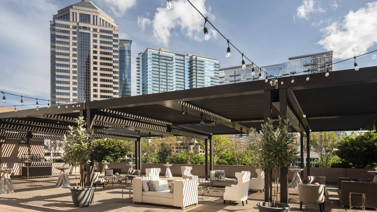 Fifth-floor rooftop terrace during the day with modern white sofas under large wood pergola