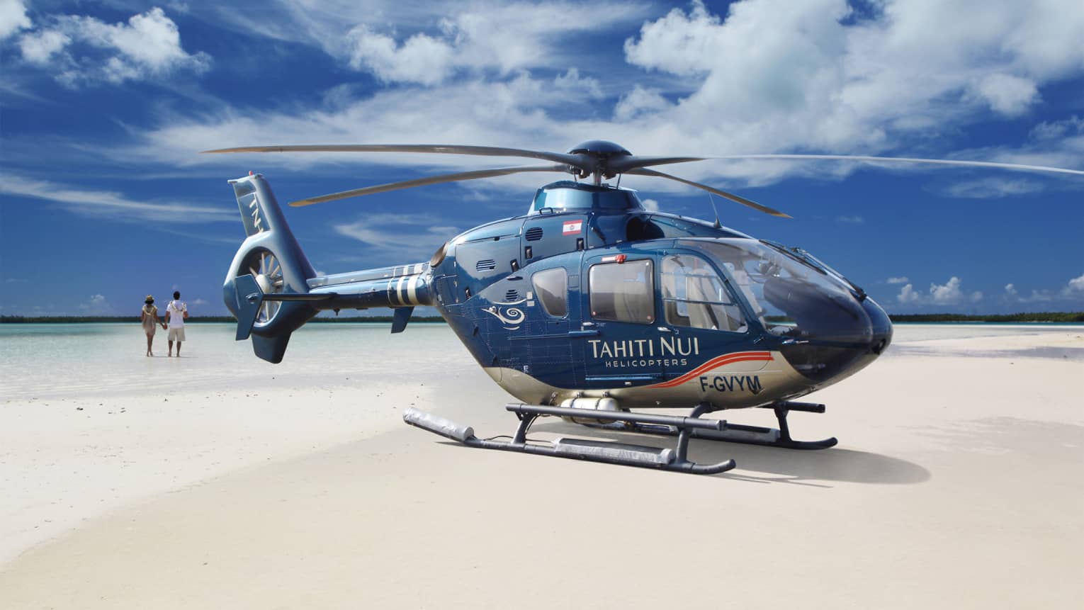 Guests walk on the beach before boarding the Tahiti Nui Helicopter for an island tour