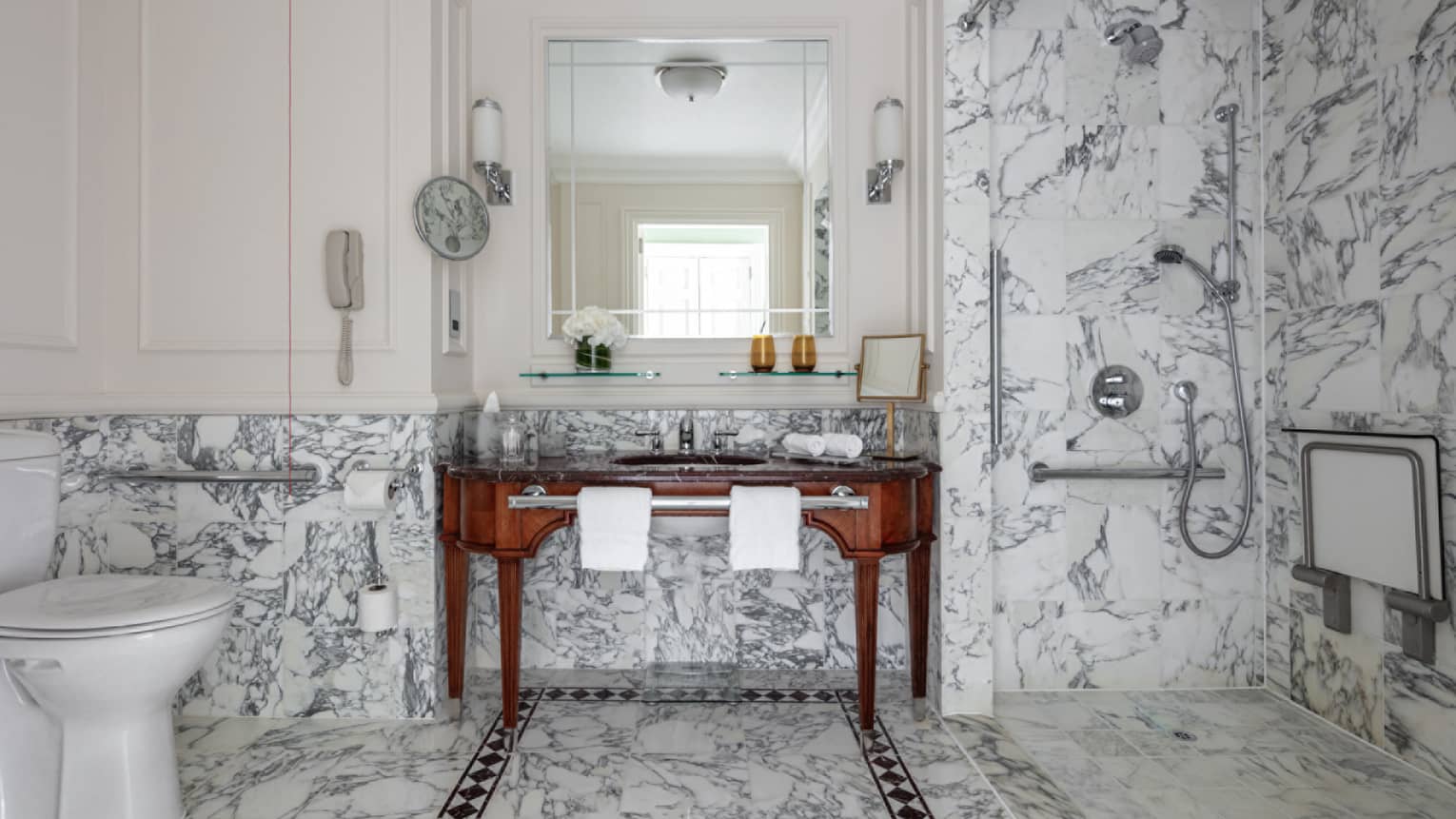 Bathroom with marble shower and glass door, porcelain commode, double wooden vanity, mirror