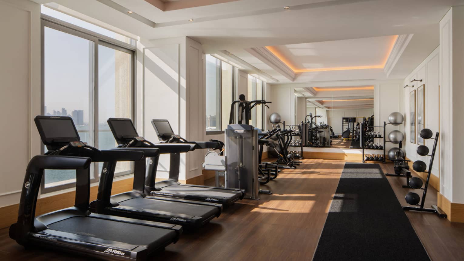 Fitness centre with three treadmills, sea and Doha view