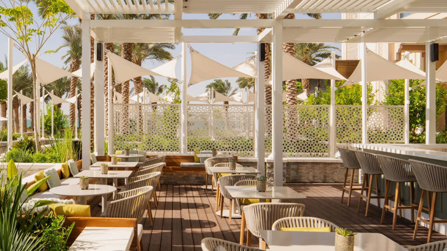 Outdoor restaurant terrace set underneath white pergola