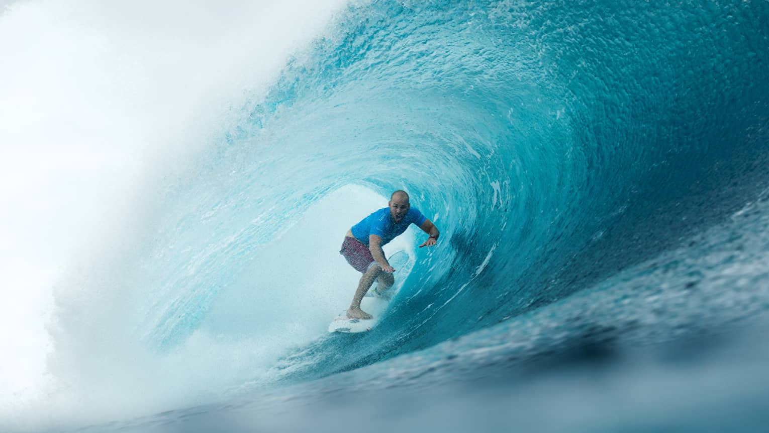 Man on surfboard surfs along large waves in remote Outer Atolls