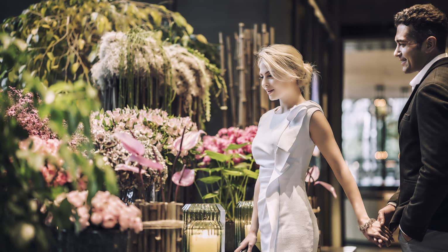 Woman and man admire large floral arrangements in hotel