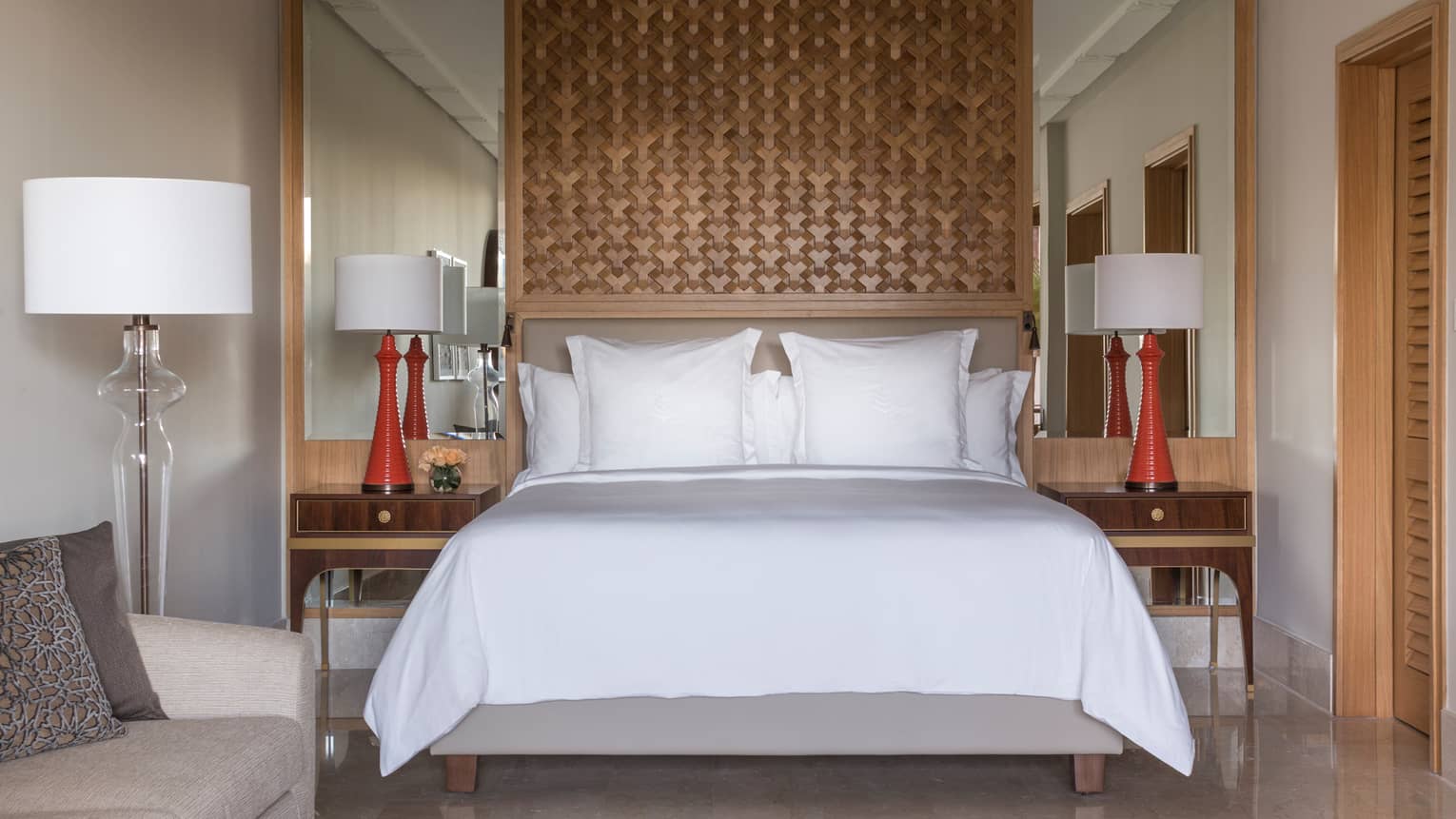 Deluxe Room bed under lattice wood panel, red lamps on nightstands