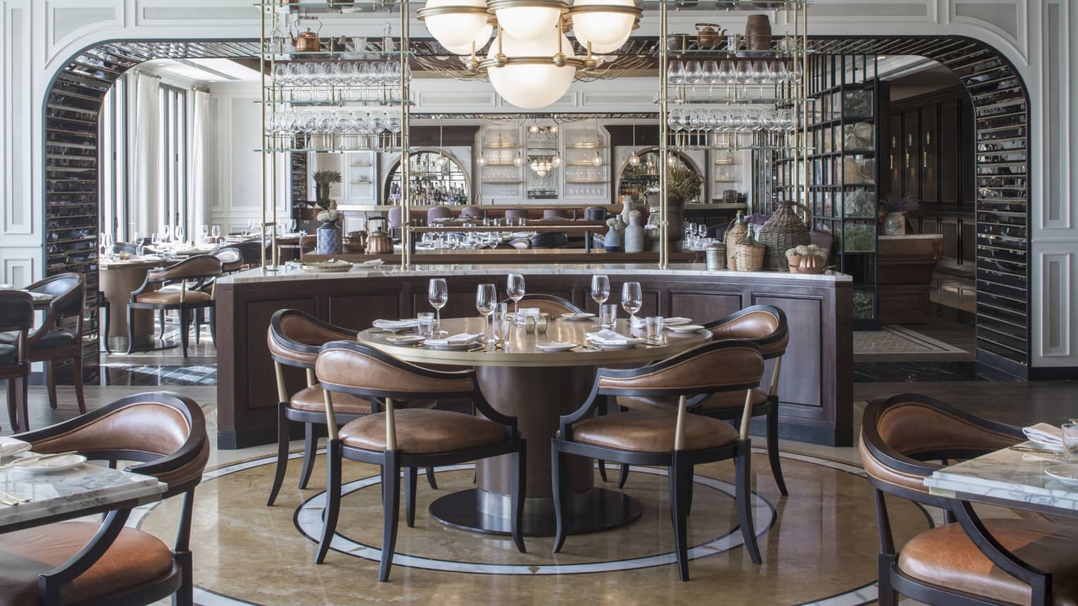 An art-deco restaurant features tables with low-back brown-leather chairs and a counter with copper kettles and wicker jugs.