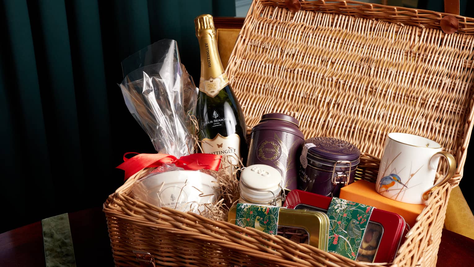 Picnic hamper filled with champagne bottle, jarred teas, mug, and assorted nuts and candies,Picnic hamper filled with champagne bottle, jarred teas, mug, and assorted nuts and candies