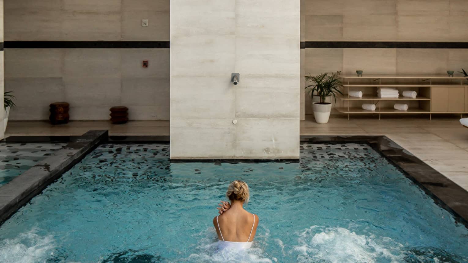 A person swimming in an outdoor pool with a sun roof.