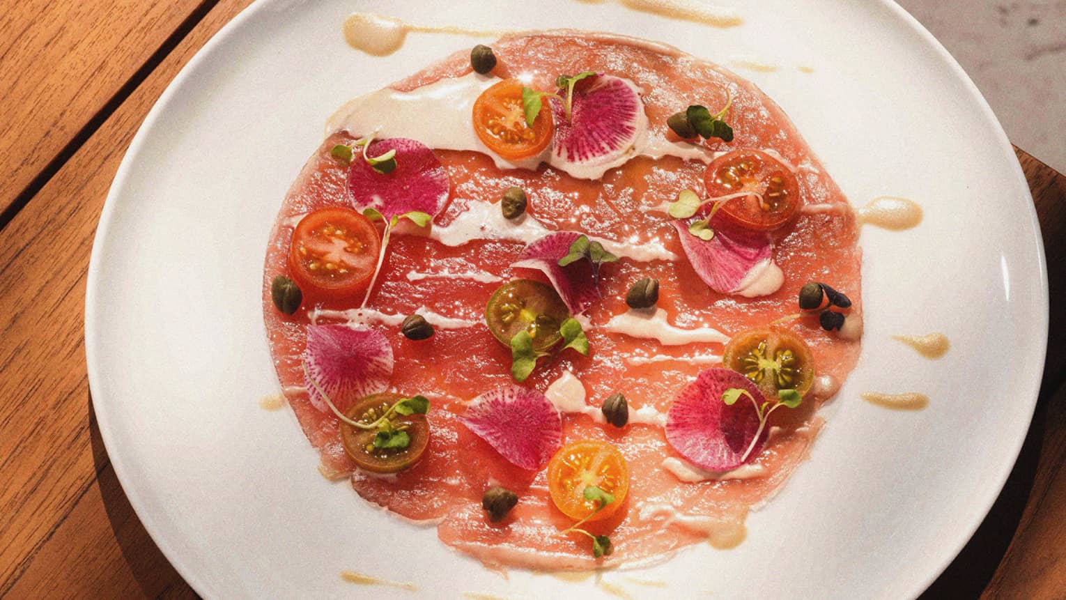 Tuna carpaccio served on a wide white plate
