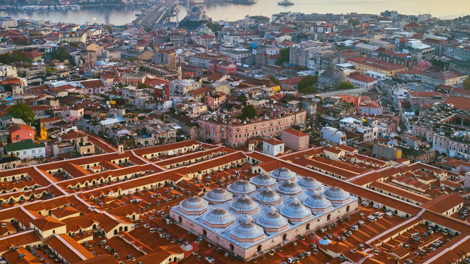Aerial view of city rooftops, buildings and bridge at sunset
