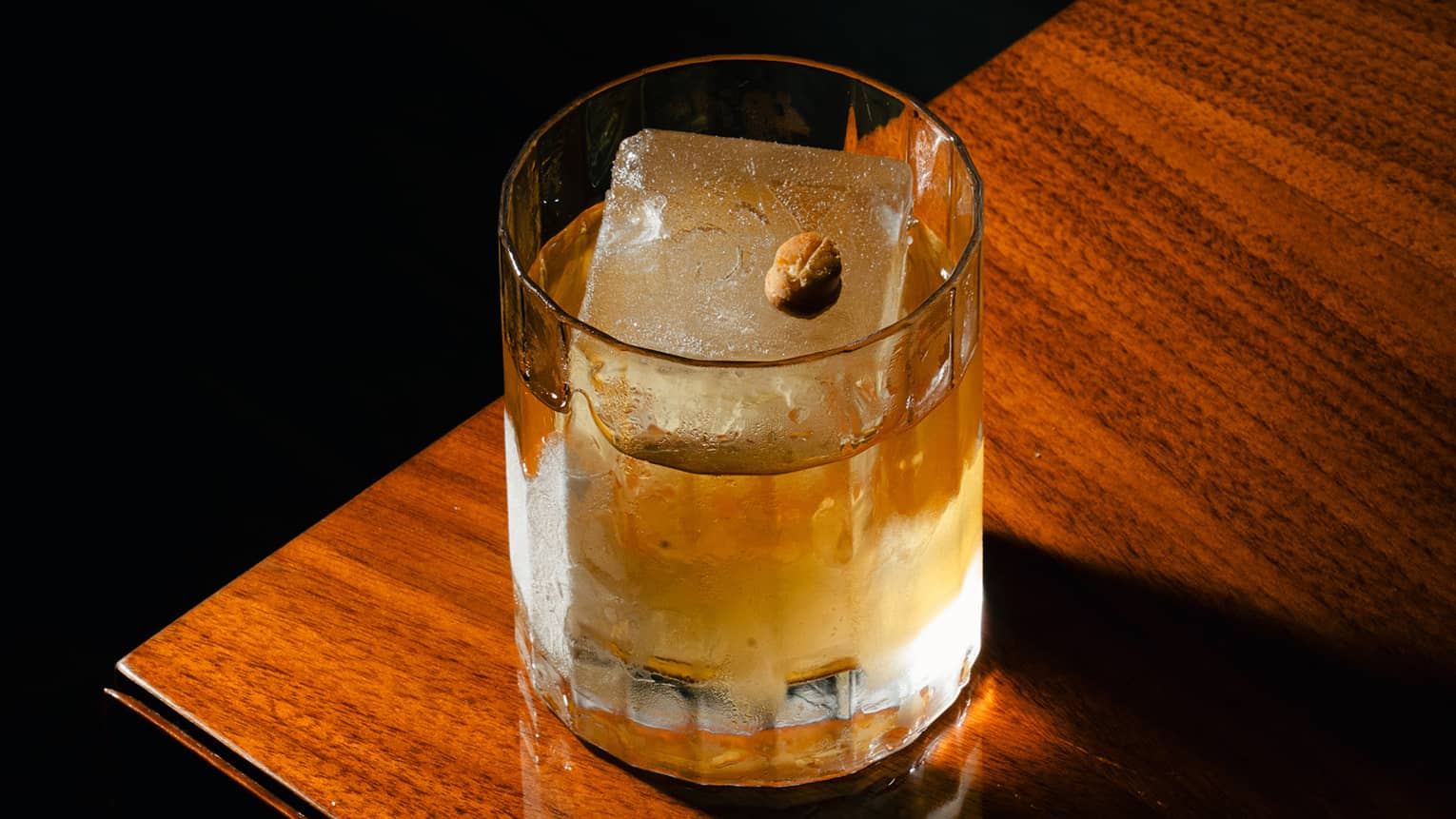 Cocktail in a rocks glass with one large ice cube