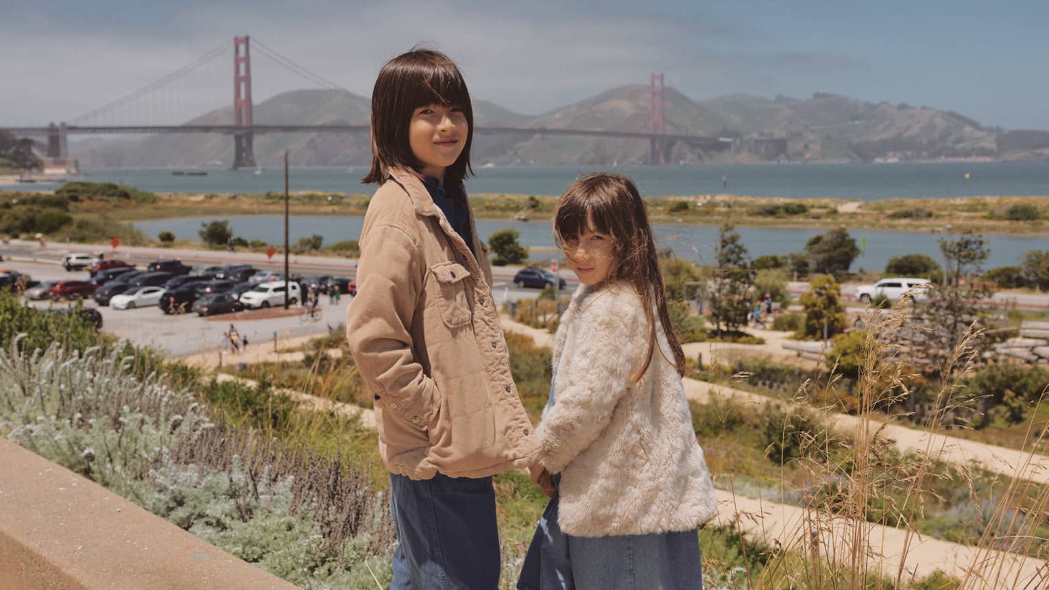 Two children turn to face the camera with the Golden Gate Bridge in the background.