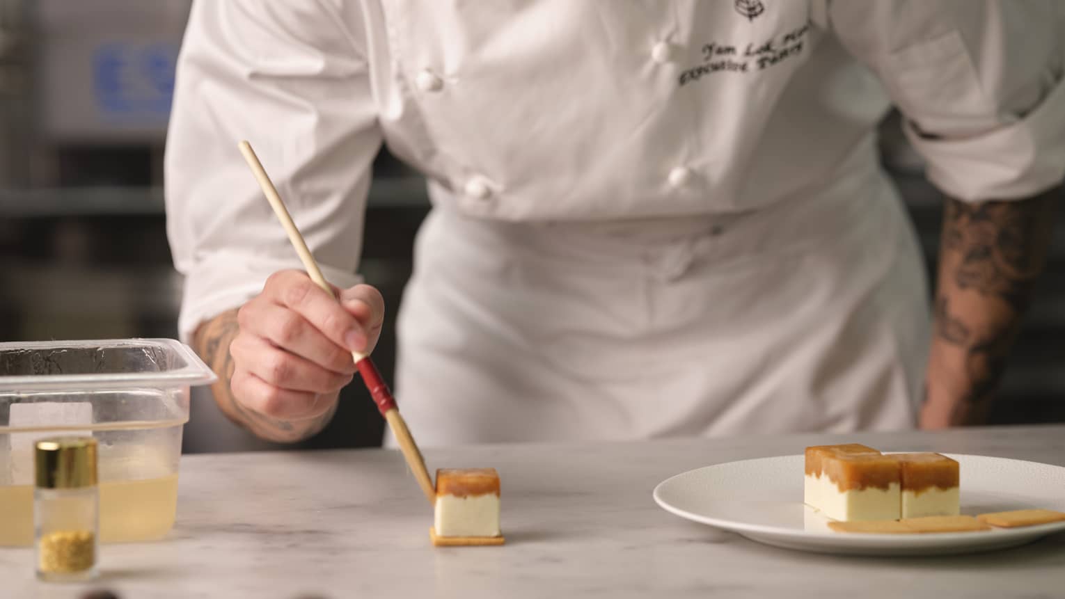 A chef paints small cakes using a paintbrush.