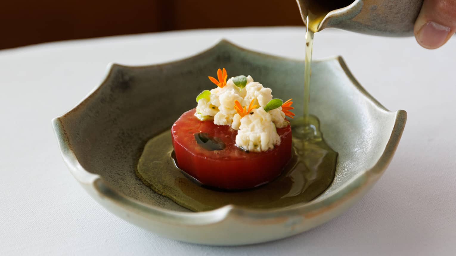 A tomato with oil being poured over it.