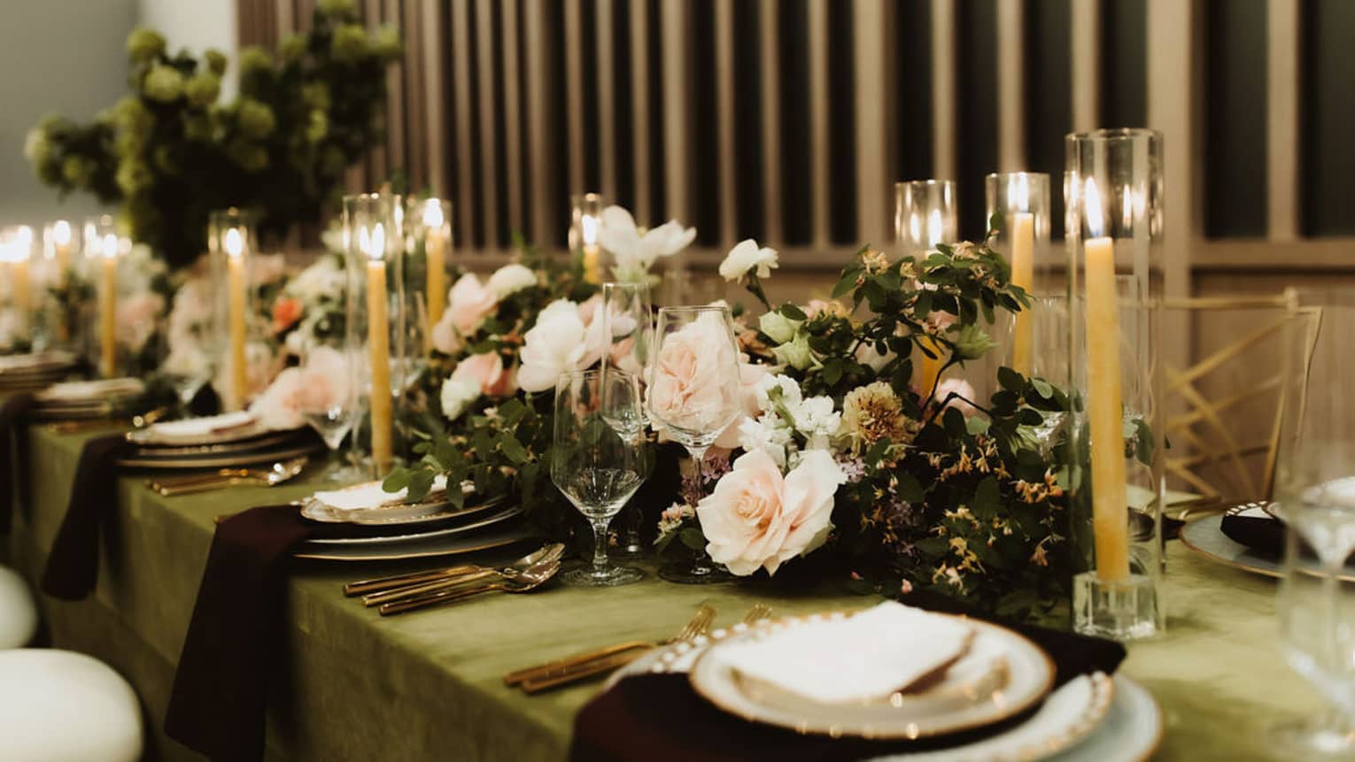 A long table with candles, flowers, plates and utensils.