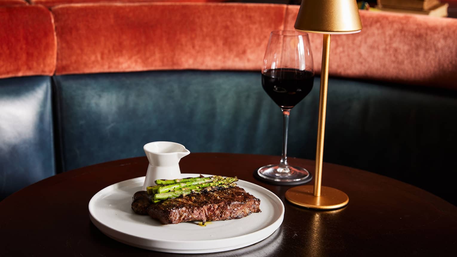 Steak and asparagus on a dining table with a glass of wine.