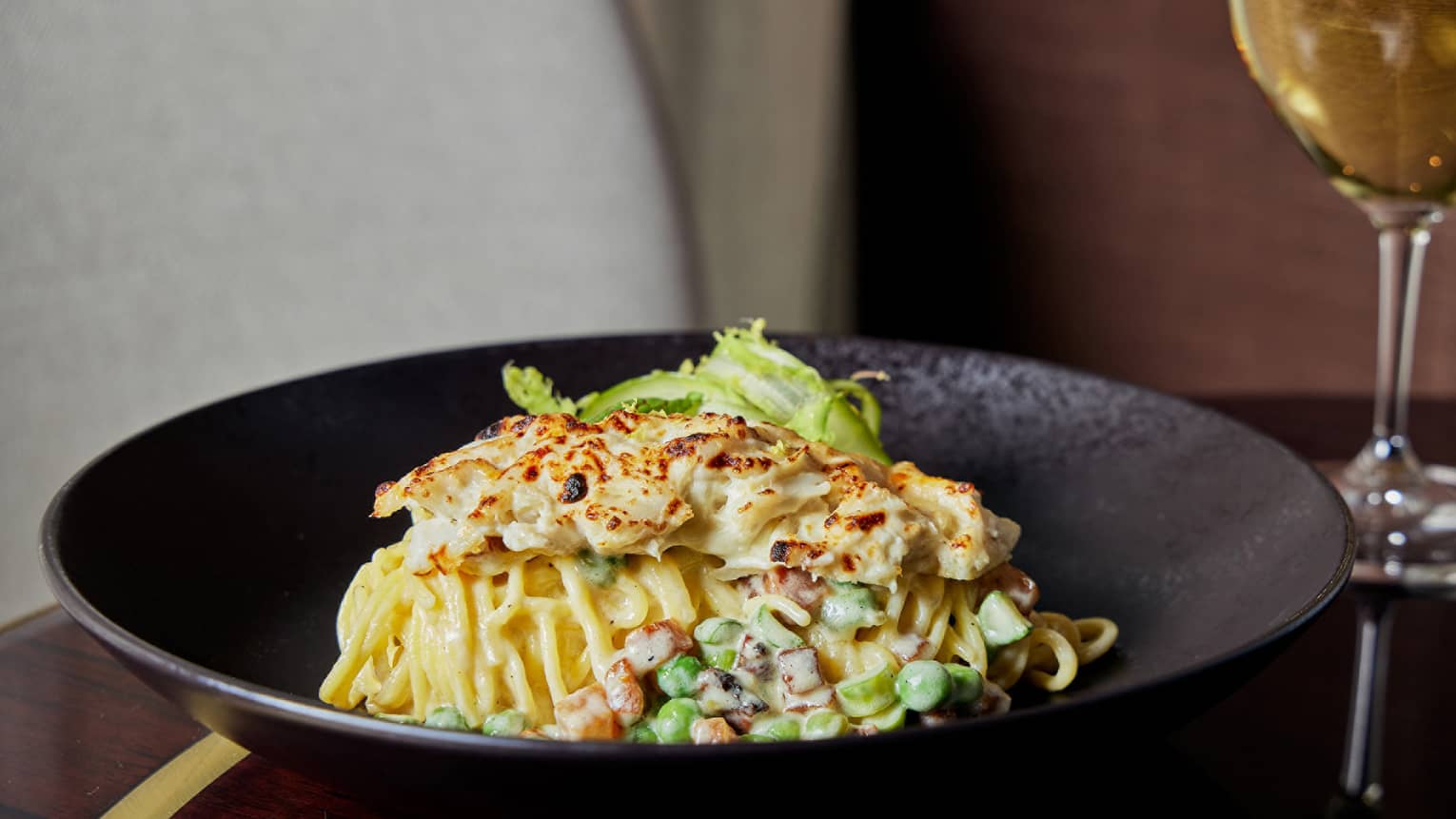 A crab pasta with a cream sauce in a black bowl.