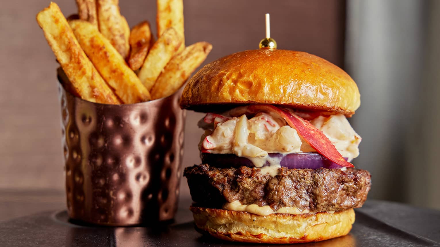 A burger and fries on a black plate.