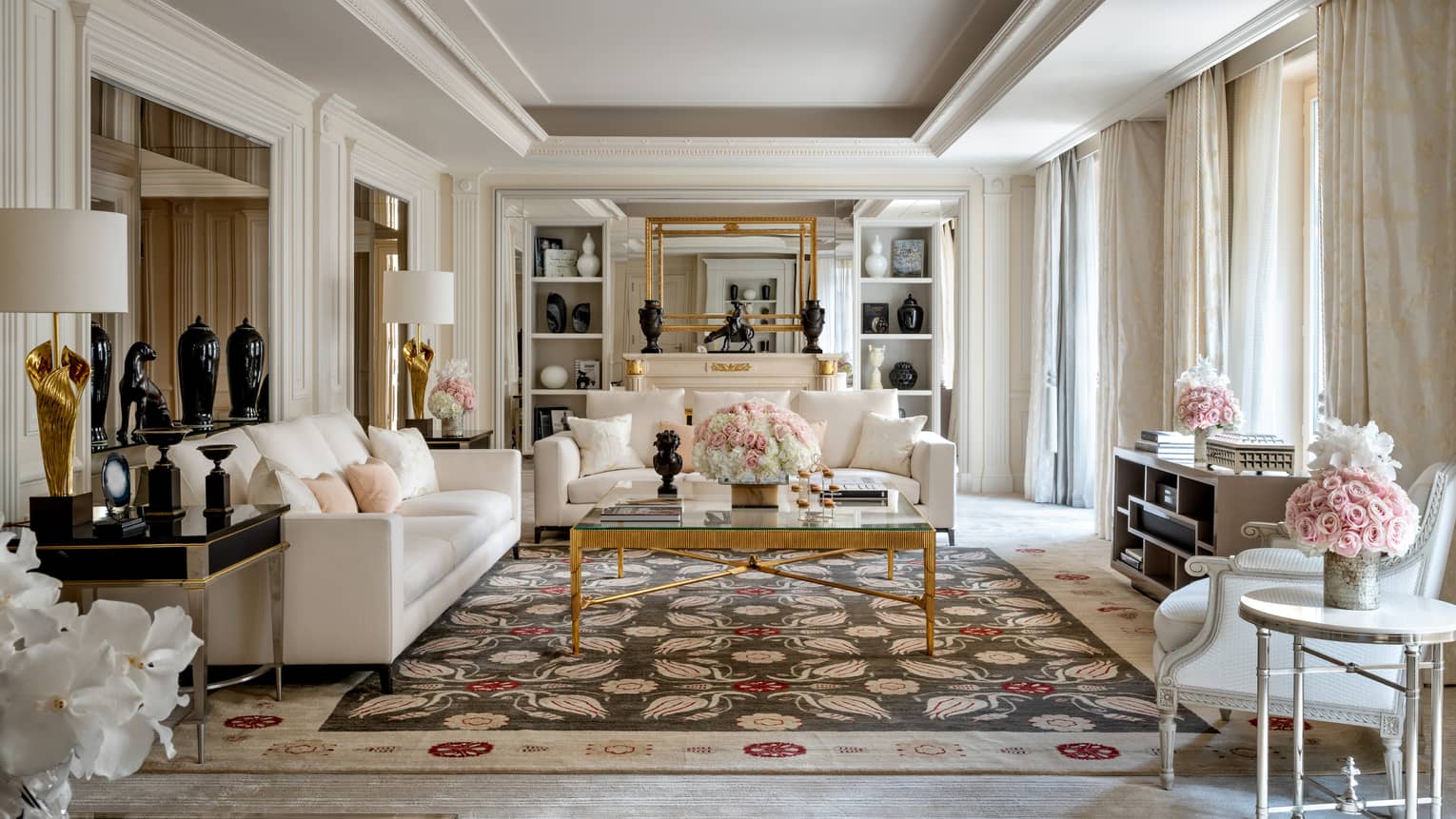 Royal Suite spacious, sunny seating area with white sofa and chairs, statues, flowers 