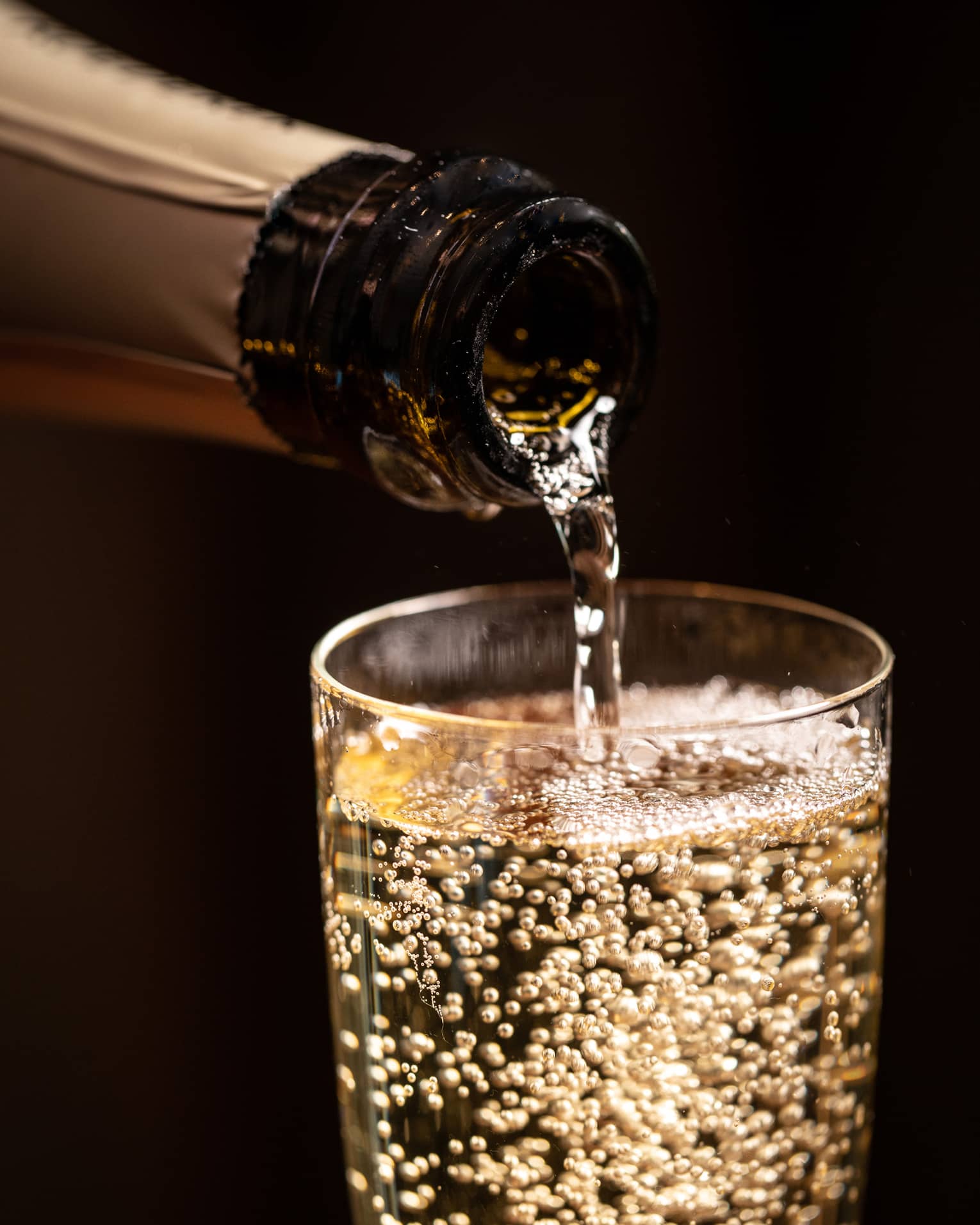 A bottle of wine being poured into a glass.